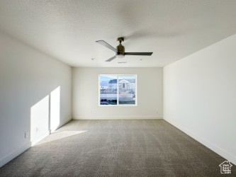 Carpeted empty room with a ceiling fan and baseboards