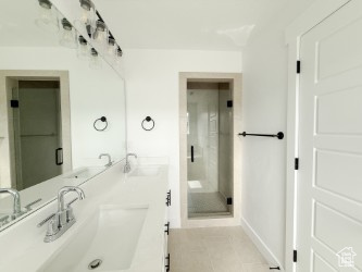 Bathroom with double vanity, a stall shower, and tile patterned flooring
