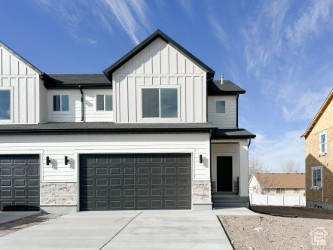 View of front facade featuring board and batten siding, an attached garage, stone siding, and concrete driveway