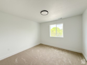 Empty room featuring baseboards and light carpet