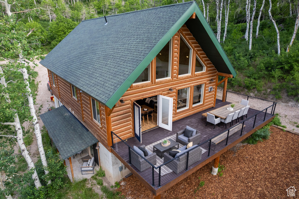 Rear view of property featuring an outdoor living space, roof with shingles, and a deck