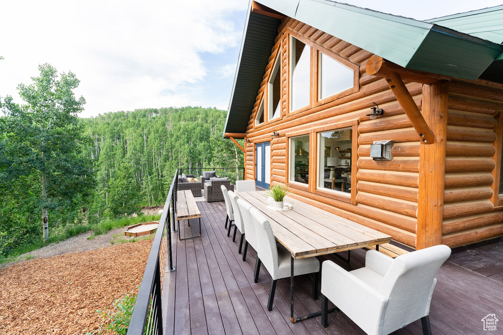 Wooden deck with outdoor dining space, outdoor lounge area, and a view of trees