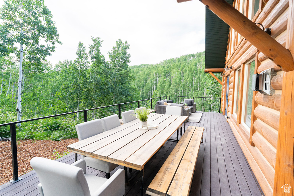 Deck featuring a view of trees, an outdoor hangout area, and outdoor dining area