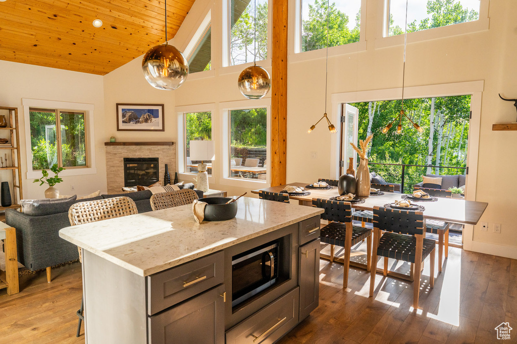 Kitchen featuring high vaulted ceiling, stainless steel microwave, wooden ceiling, hardwood / wood-style floors, and open floor plan