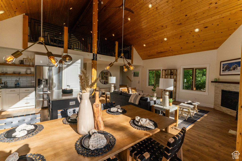 Dining space featuring wood ceiling, high vaulted ceiling, wood finished floors, a fireplace, and recessed lighting