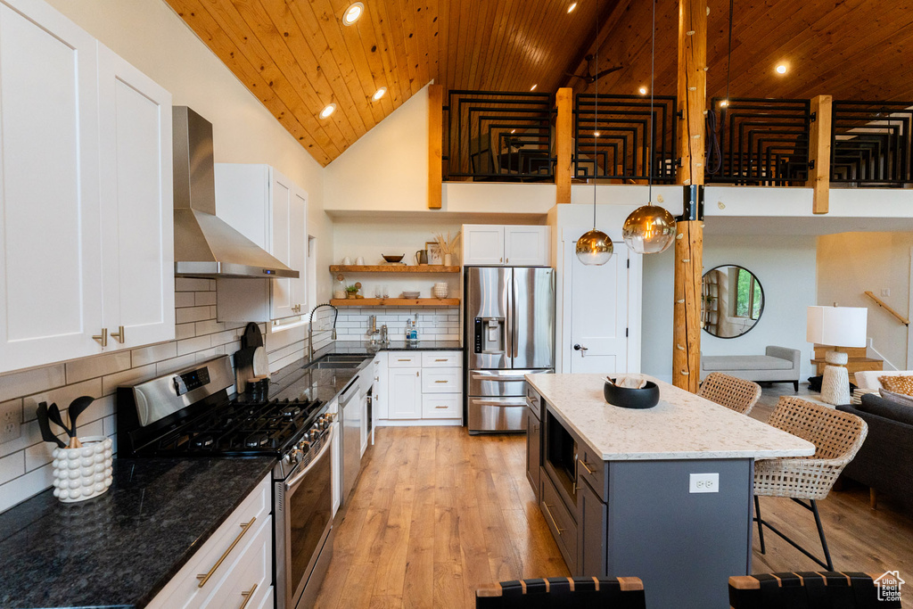 Kitchen with stainless steel appliances, wall chimney range hood, wooden ceiling, a breakfast bar area, and open shelves