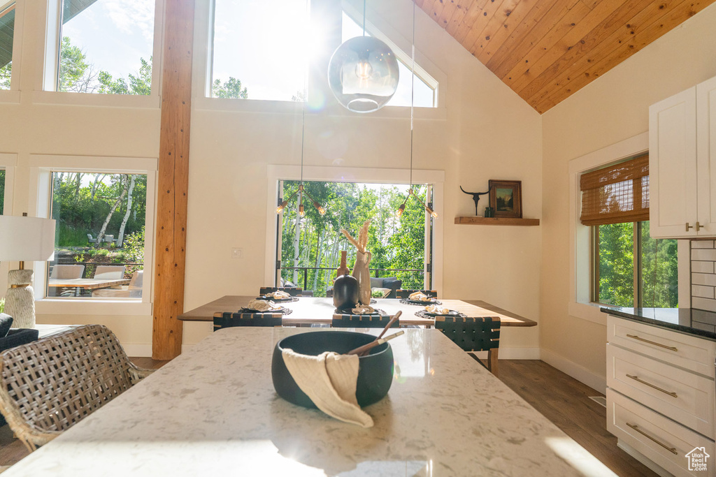 Dining room with high vaulted ceiling, dark wood-style floors, and wooden ceiling