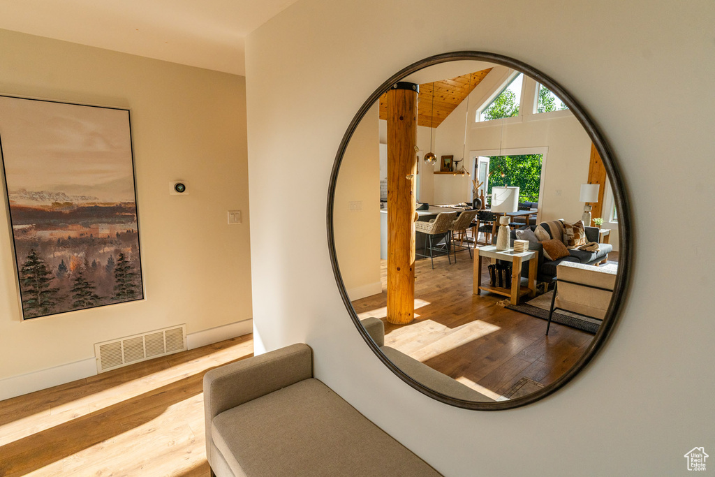 Corridor with wood finished floors and lofted ceiling