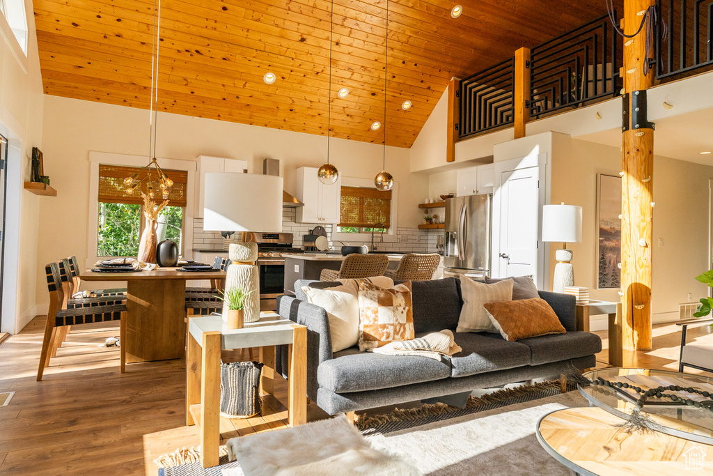 Living room with high vaulted ceiling, wooden ceiling, and light wood-style flooring