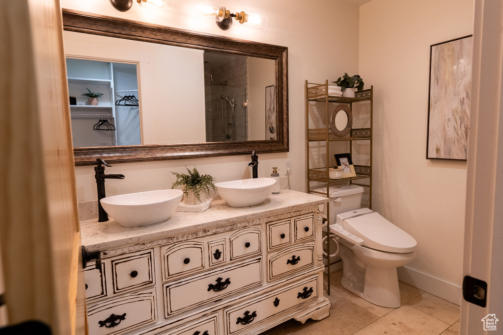 Full bath with double vanity, a shower, and tile patterned flooring