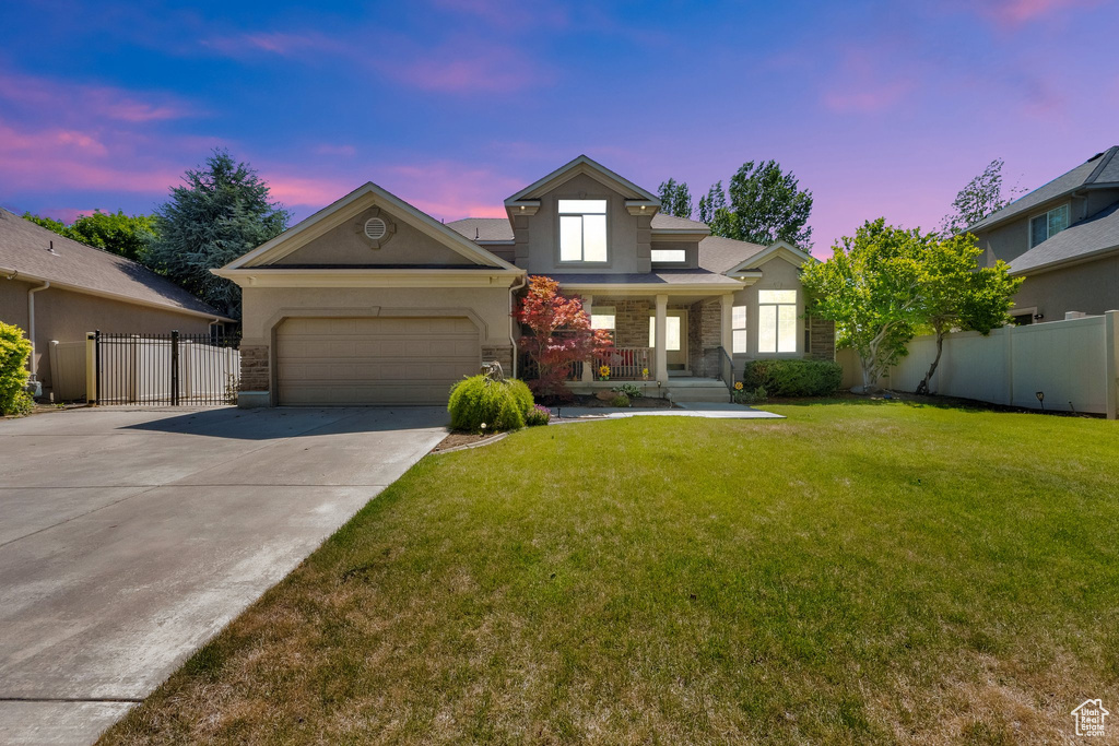 View of front of house with a porch, a garage, driveway, and stone siding