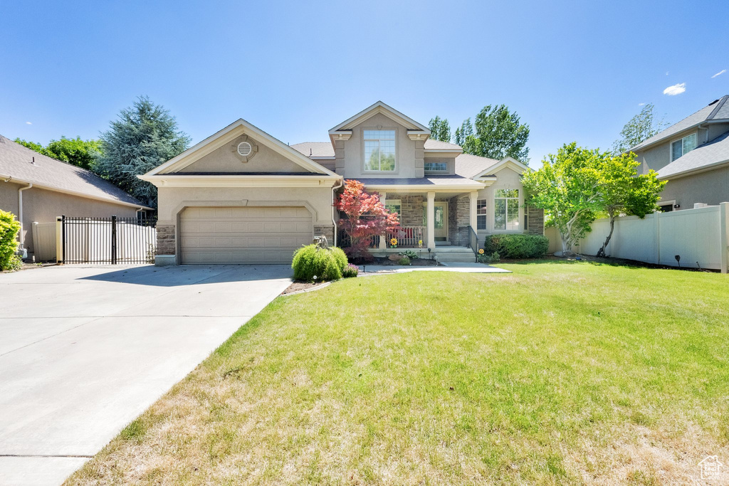 View of front of home with stone siding, driveway, stucco siding, covered porch, and an attached garage