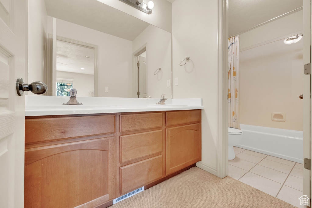 Full bath with double vanity, shower / tub combo with curtain, and tile patterned floors