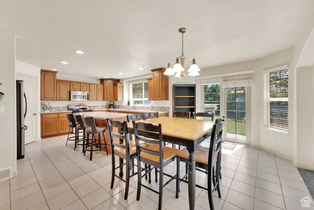 Dining area with a chandelier, light tile patterned floors, and recessed lighting
