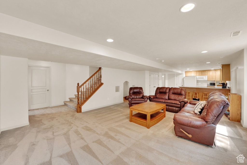 Living room featuring light carpet, stairs, recessed lighting, and arched walkways