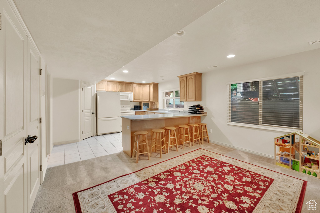 Kitchen featuring white appliances, recessed lighting, a peninsula, light tile patterned floors, and light countertops