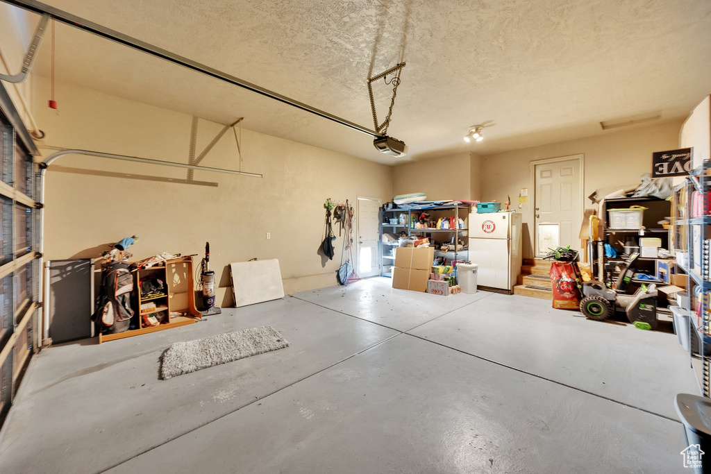 Garage featuring freestanding refrigerator and a garage door opener