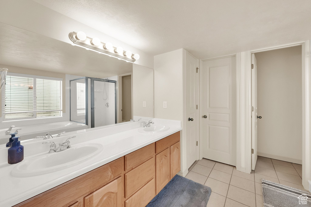 Full bathroom with tile patterned flooring, a stall shower, double vanity, and a garden tub