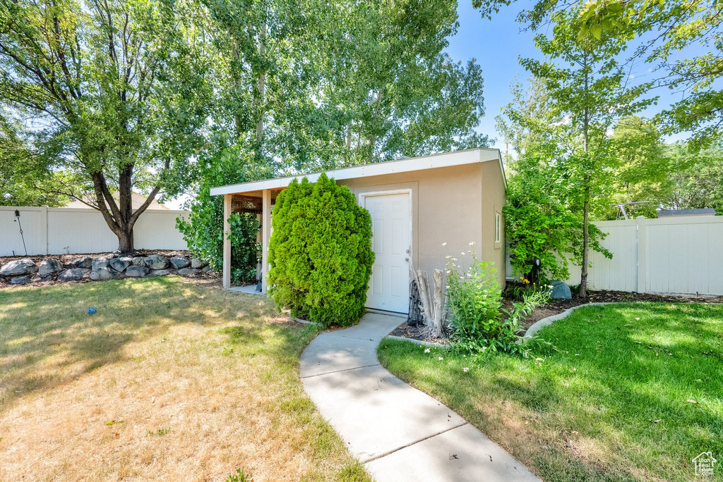View of front of property featuring stucco siding, a fenced backyard, and an outbuilding