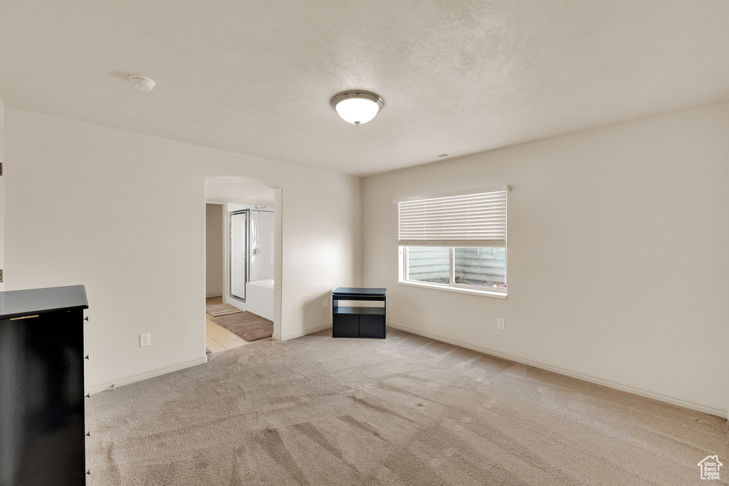Unfurnished living room featuring arched walkways and carpet floors