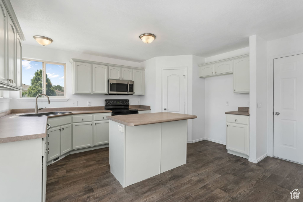 Kitchen featuring stainless steel microwave, black electric range, dark wood-type flooring, and a kitchen island