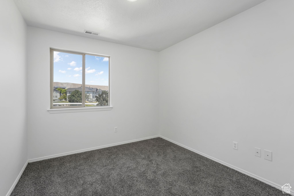 Spare room with dark colored carpet and a textured ceiling