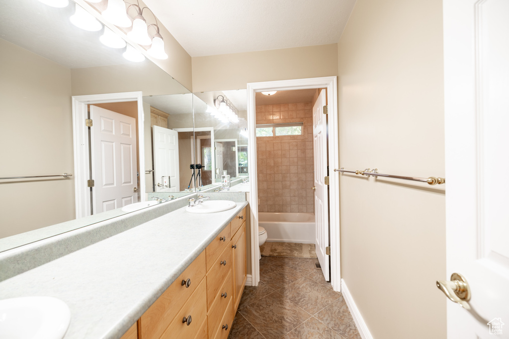 Bathroom with double vanity, tile patterned floors, and  shower combination