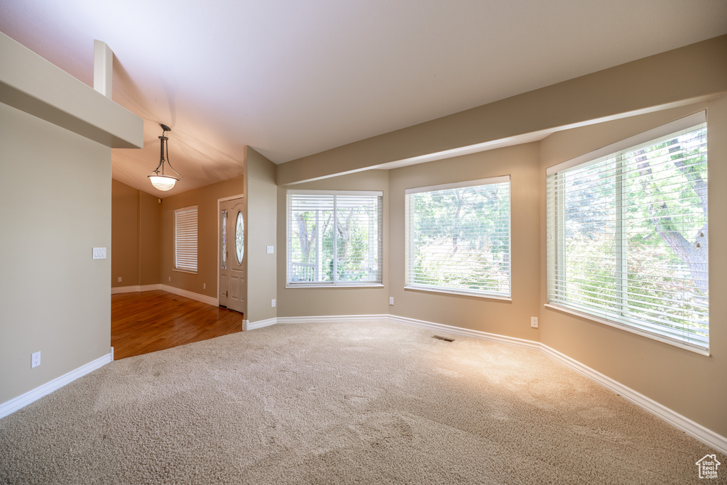 Empty room featuring carpet floors, healthy amount of natural light, and lofted ceiling