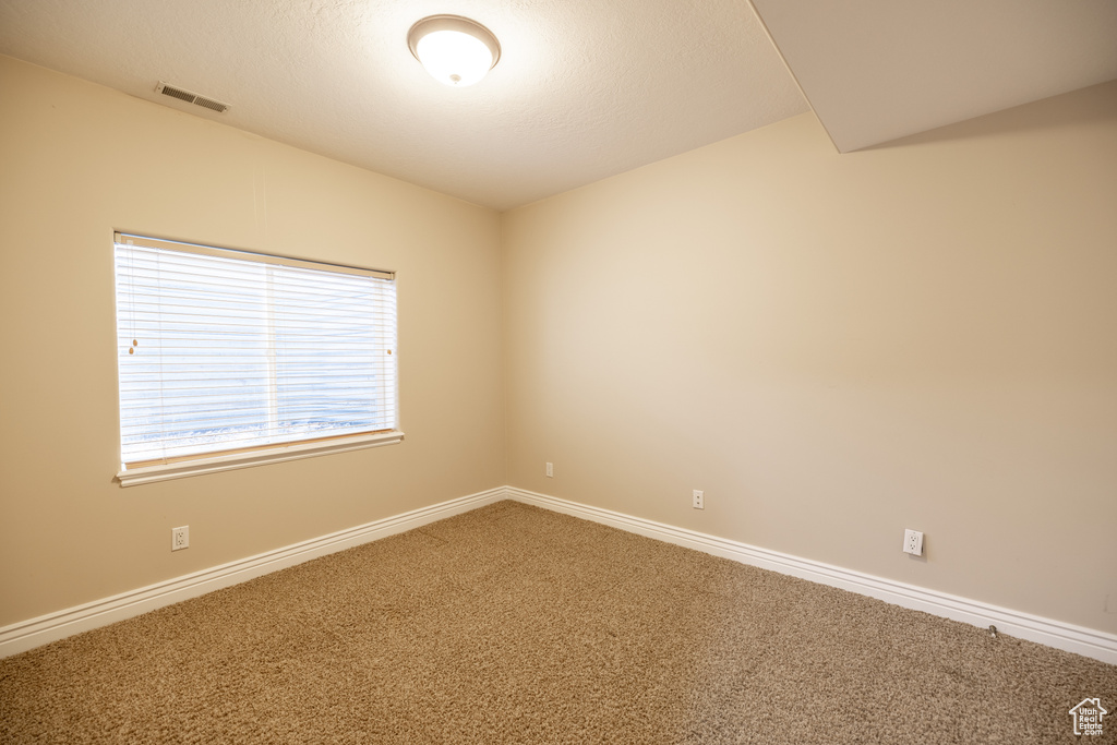 Carpeted spare room featuring baseboards