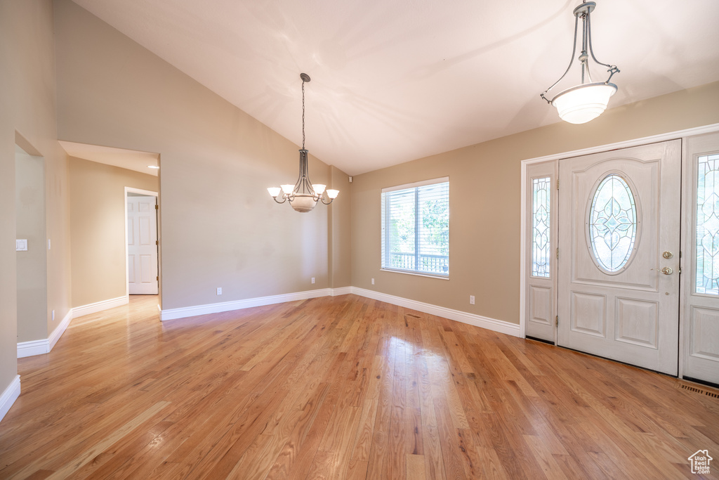 Foyer entrance featuring a chandelier, light wood finished floors, and high vaulted ceiling