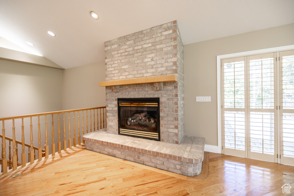 Unfurnished living room featuring wood finished floors, lofted ceiling, recessed lighting, and a fireplace