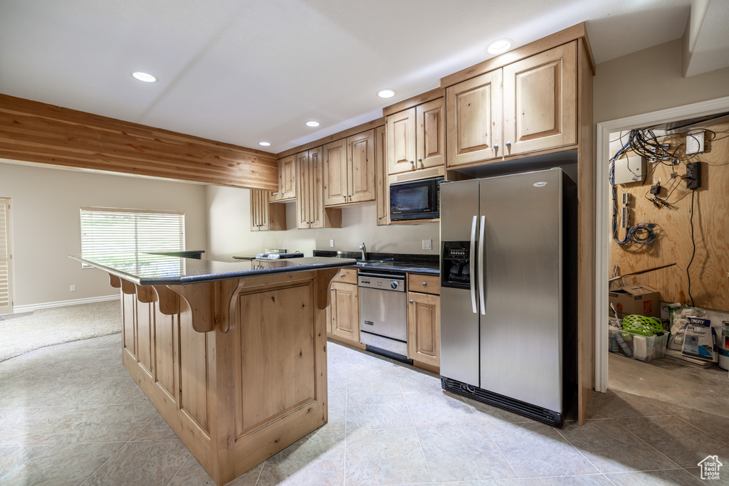 Kitchen featuring stainless steel appliances, recessed lighting, dark countertops, a kitchen breakfast bar, and a kitchen island