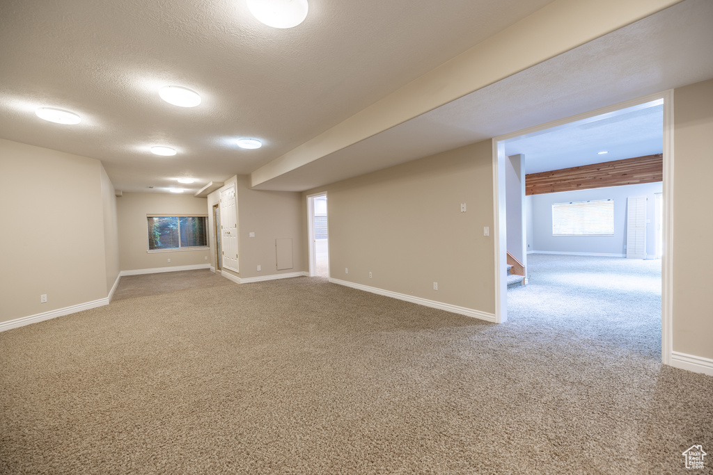 Below grade area featuring carpet, stairway, and a textured ceiling