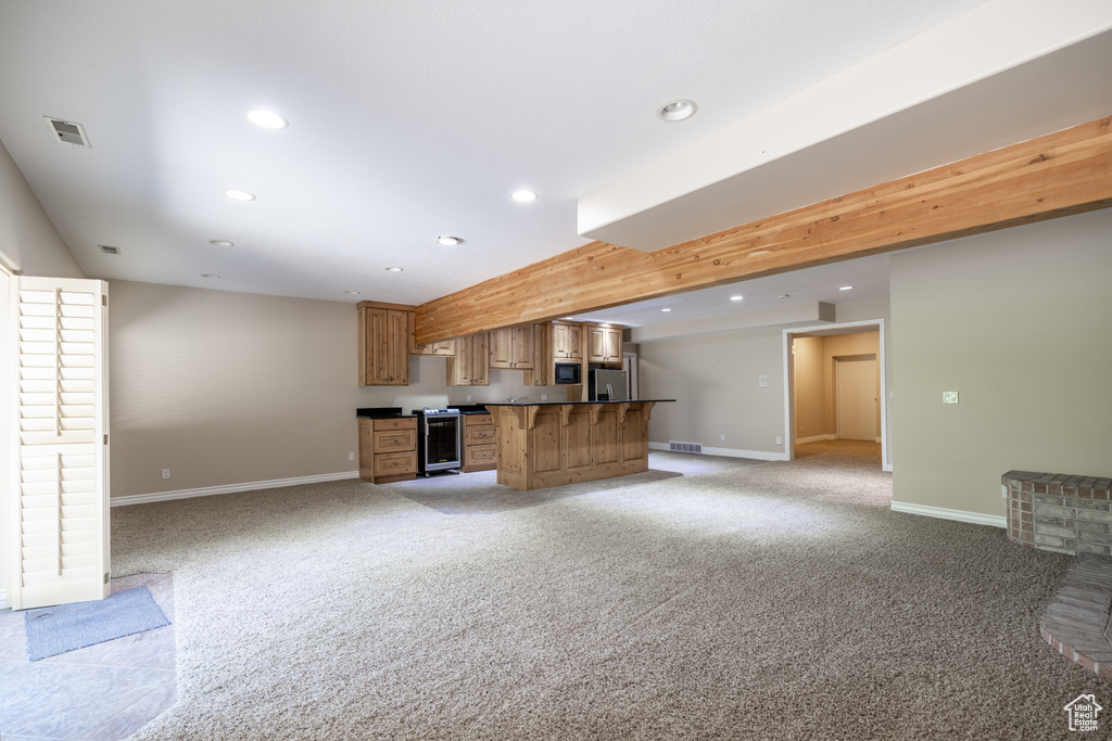 Unfurnished living room featuring light colored carpet, recessed lighting, and bar with sink