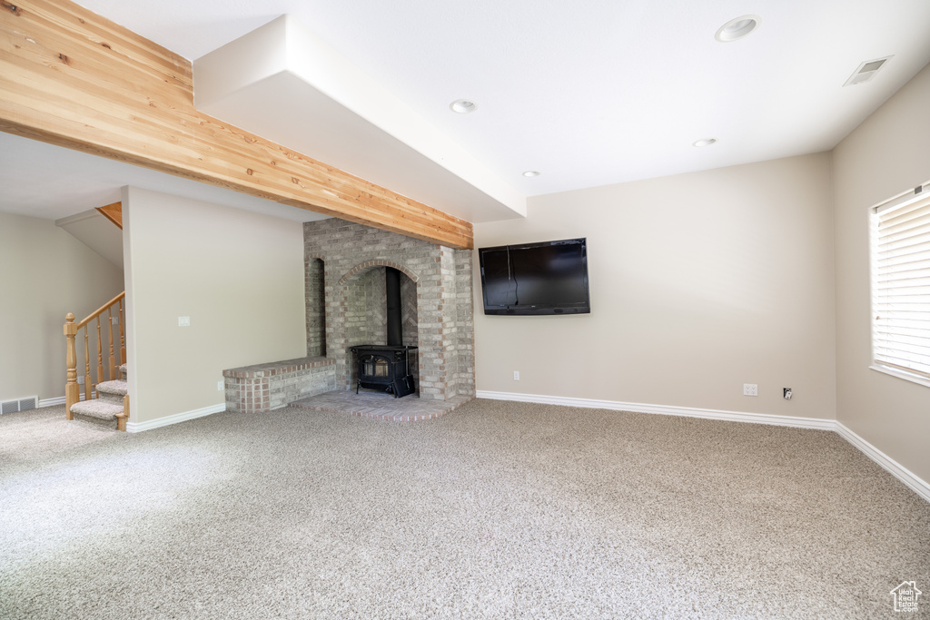 Unfurnished living room with a wood stove, carpet, stairway, and recessed lighting