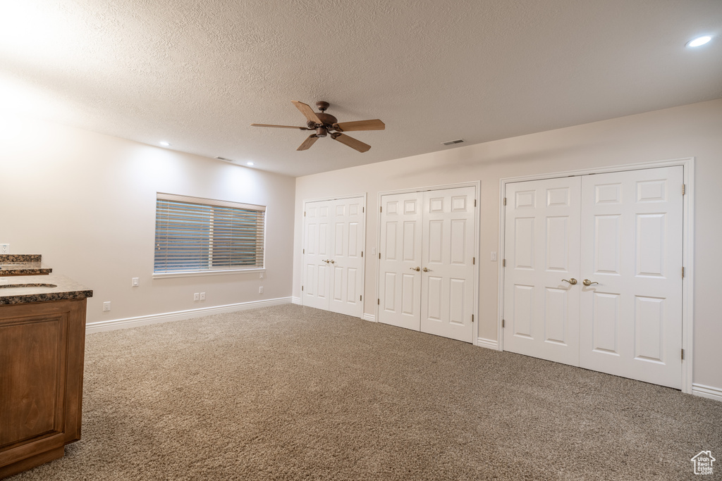 Unfurnished bedroom featuring multiple closets, carpet floors, recessed lighting, a textured ceiling, and ceiling fan
