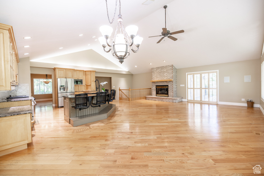 Kitchen with stainless steel appliances, light brown cabinets, lofted ceiling, ceiling fan, and a stone fireplace
