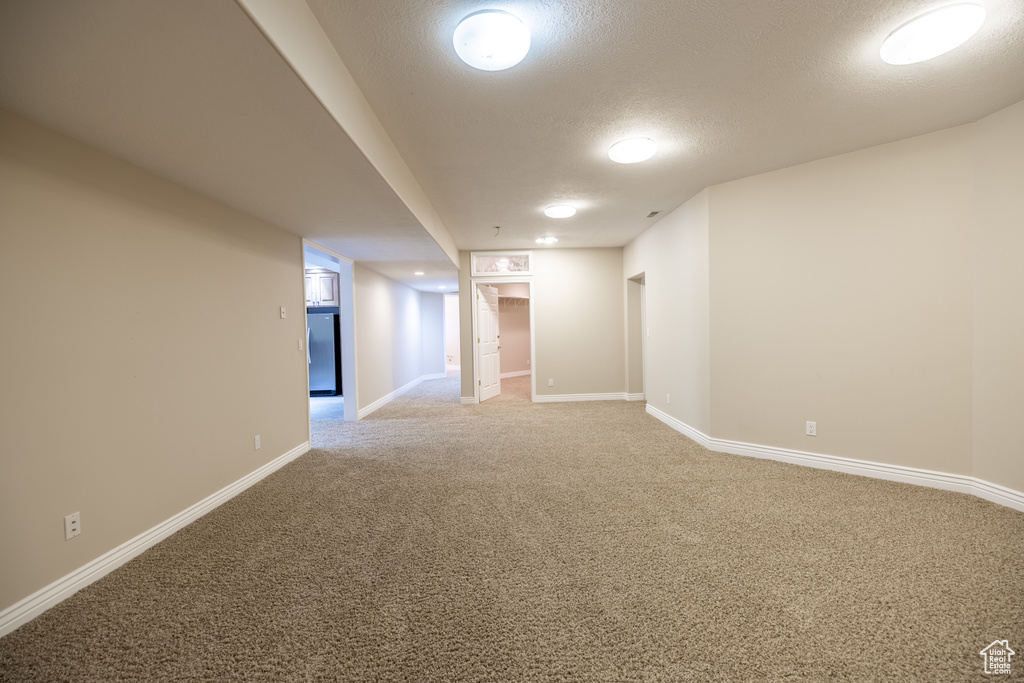 Unfurnished room featuring light carpet and a textured ceiling