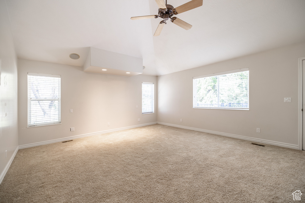 Carpeted empty room featuring ceiling fan and lofted ceiling
