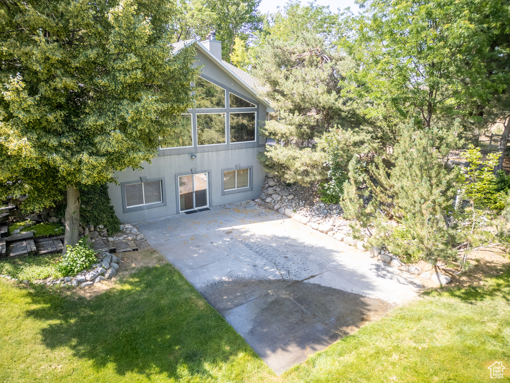 Rear view of house with a patio, a chimney, a yard, and stucco siding