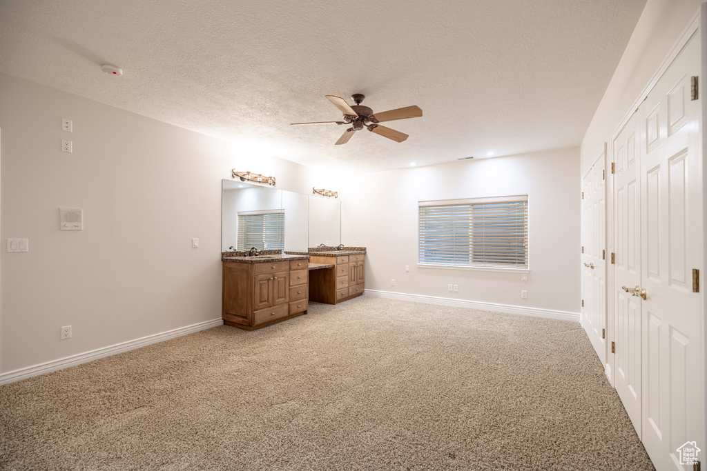 Unfurnished bedroom with light carpet, ceiling fan, and a textured ceiling