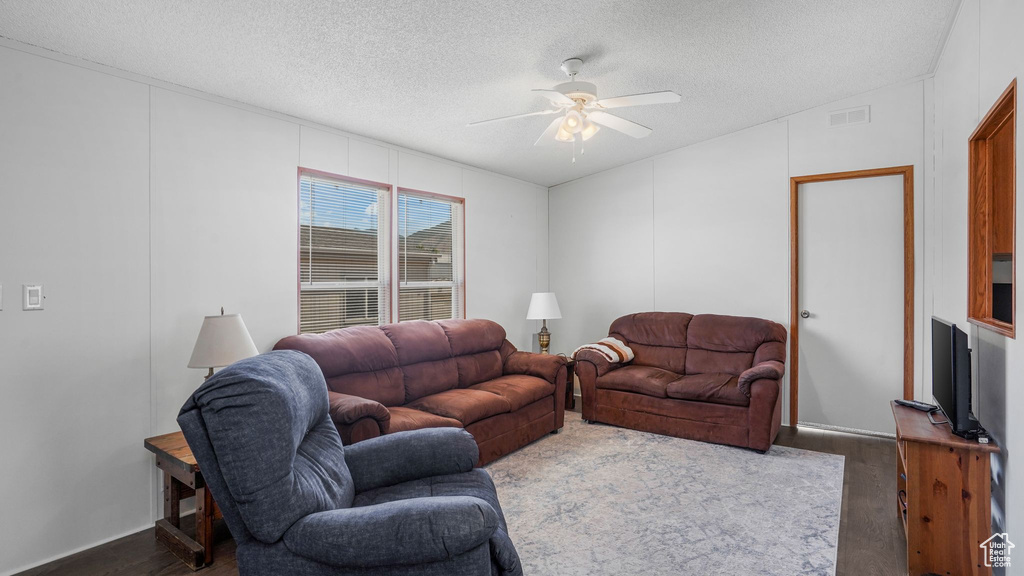 Living room with ceiling fan, dark wood-style floors, a textured ceiling, and vaulted ceiling