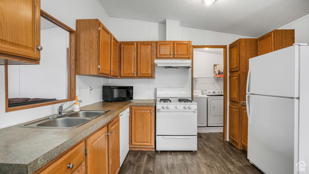 Kitchen with white appliances, washer and dryer, under cabinet range hood, dark wood-style flooring, and a textured ceiling