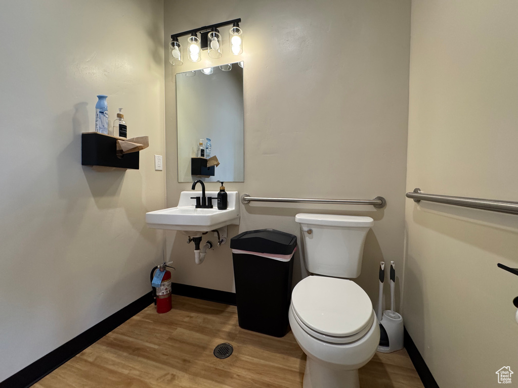 Half bathroom featuring toilet and wood finished floors