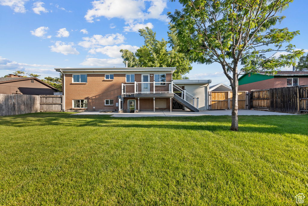 Back of house with stairway, brick siding, a gate, a fenced backyard, and a deck
