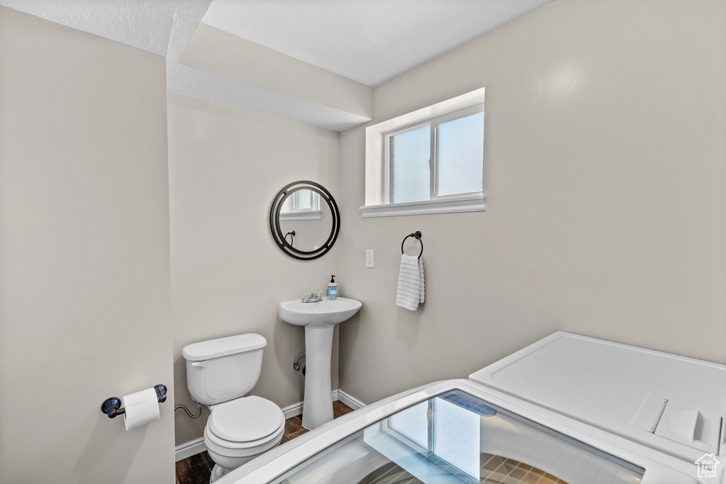 Half bath featuring toilet and wood finished floors