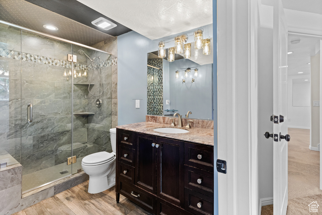 Full bathroom with a shower stall, vanity, and wood finished floors
