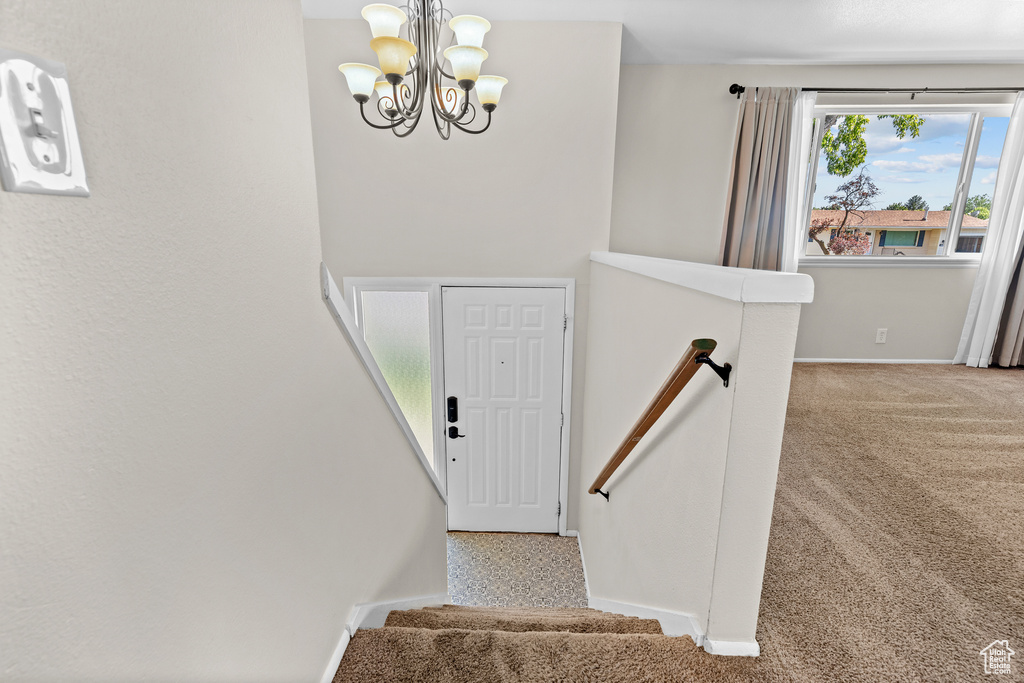 Staircase featuring a chandelier and carpet floors