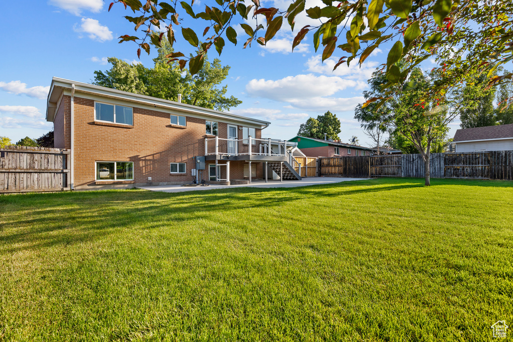 Back of property featuring stairway, brick siding, a fenced backyard, a patio, and a wooden deck