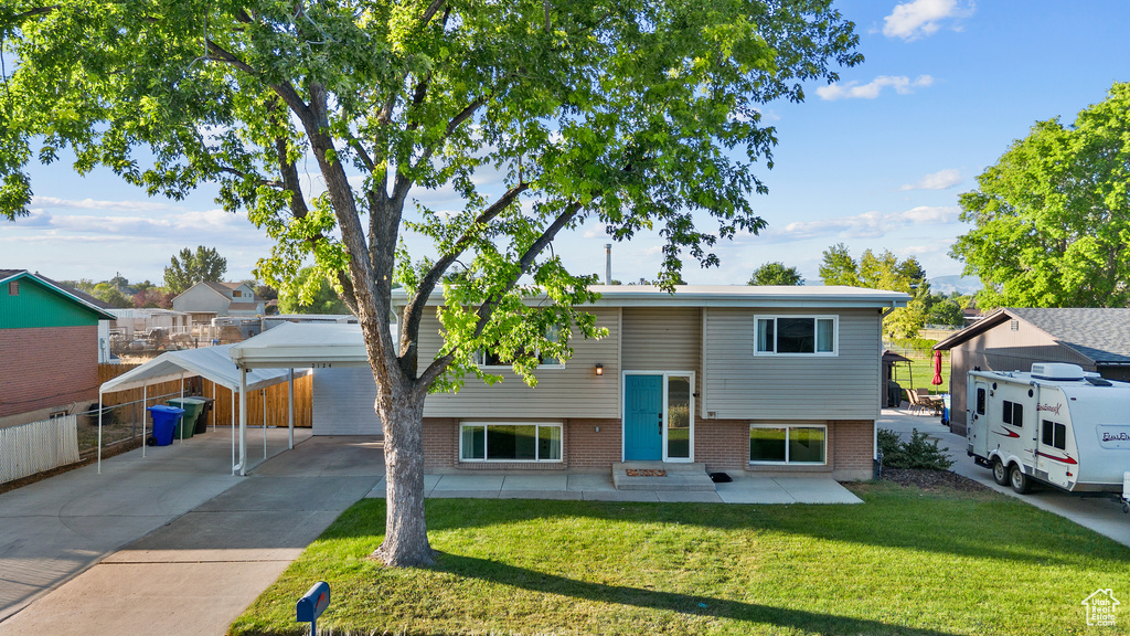 Bi-level home featuring a detached carport, entry steps, concrete driveway, and brick siding
